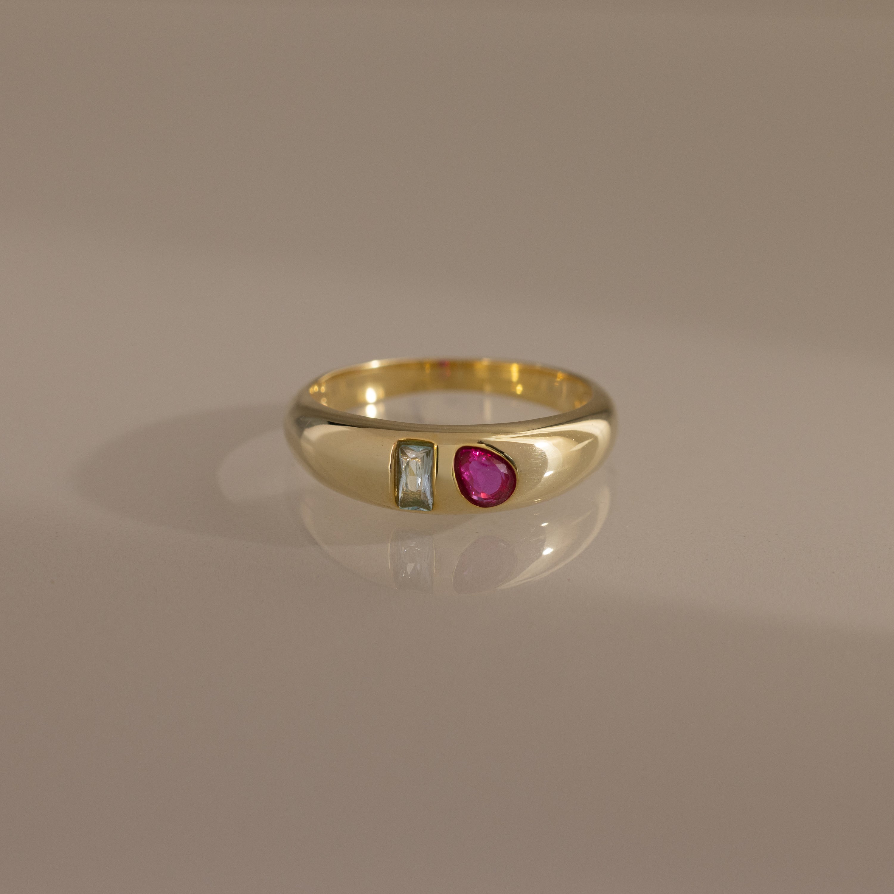 The Toi et Moi Dome Ring in 18K Gold features a rectangular clear stone and an oval pink stone set side by side on a smooth band.