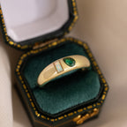 The Toi et Moi Dome Ring, showcasing green and opal stones, is displayed in a luxurious dark green velvet box with gold trim.