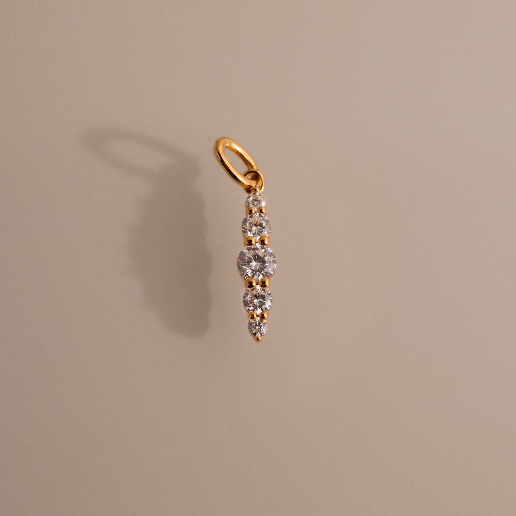 The Ombre Lace Diamond Charm features five vertically graduated round diamonds and casts a shadow on beige—a stunning gift for any birth month.