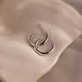 Silver stud hoop earrings on a beige stone background