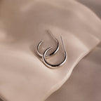 Silver stud hoop earrings on a beige stone background