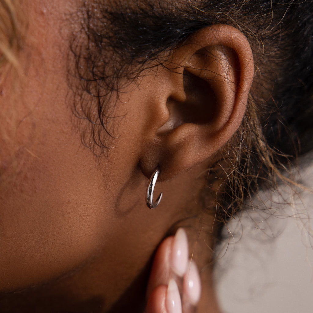 Close-up of an ear with a silver hoop stud earring.