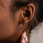 Close-up of an ear with a silver hoop stud earring.