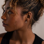 Close-up of a woman's profile with silver stud hoop earrings in a neutral background