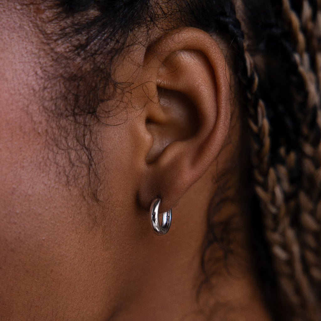 Close-up of a model wearing a silver hoop earring with braided hair.