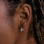 Close-up of a model wearing a silver hoop earring with braided hair.