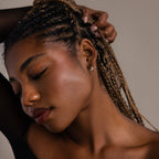 Woman with braided hair and a silver hoop earring being styled against a neutral background