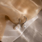 Pearl Drop Hoop earrings on a beige fabric background