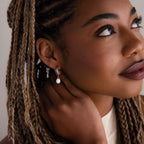 Close-up of a woman with braided hair wearing a pearl earring.