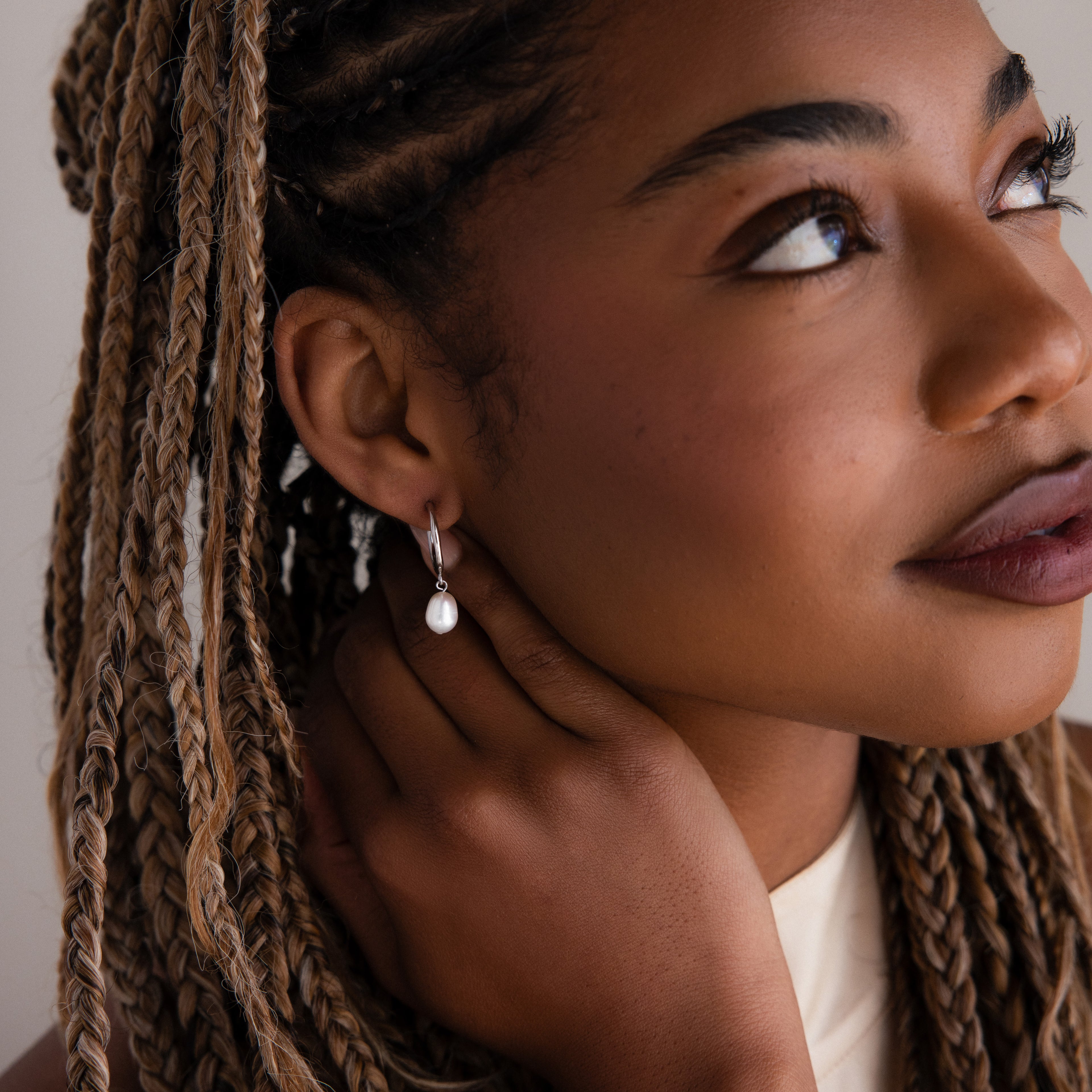 Close-up of a woman with braided hair wearing a pearl earring.