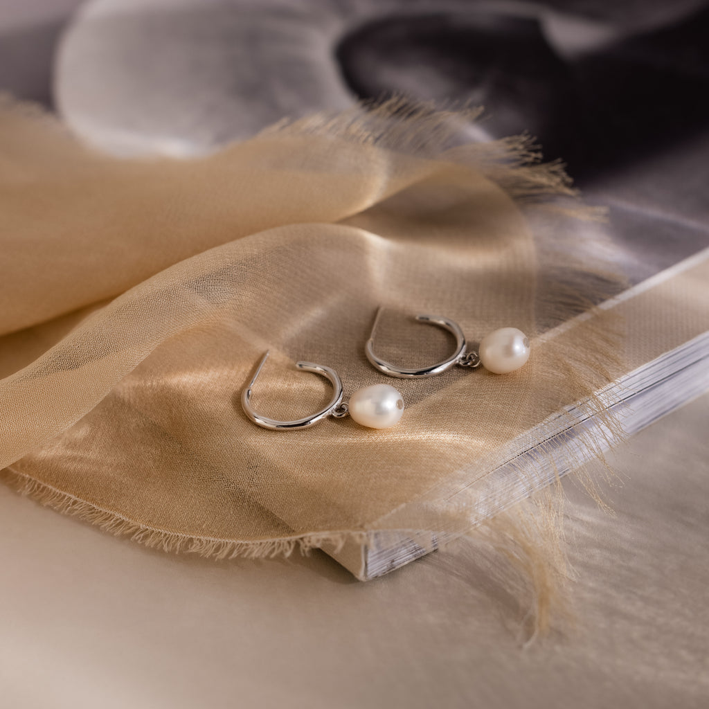Pearl earrings on a beige fabric with a blurred background