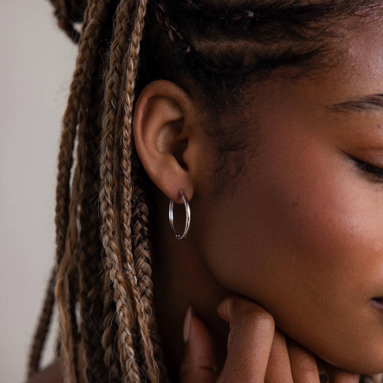 Close-up of a person wearing a silver hoop earring with braided hair.