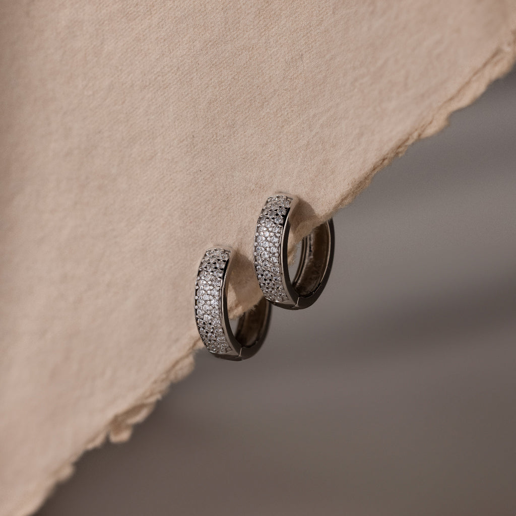 Pair of silver hoop earrings on a textured beige surface