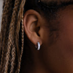 Close-up of an ear with a diamond earring and braided hair.