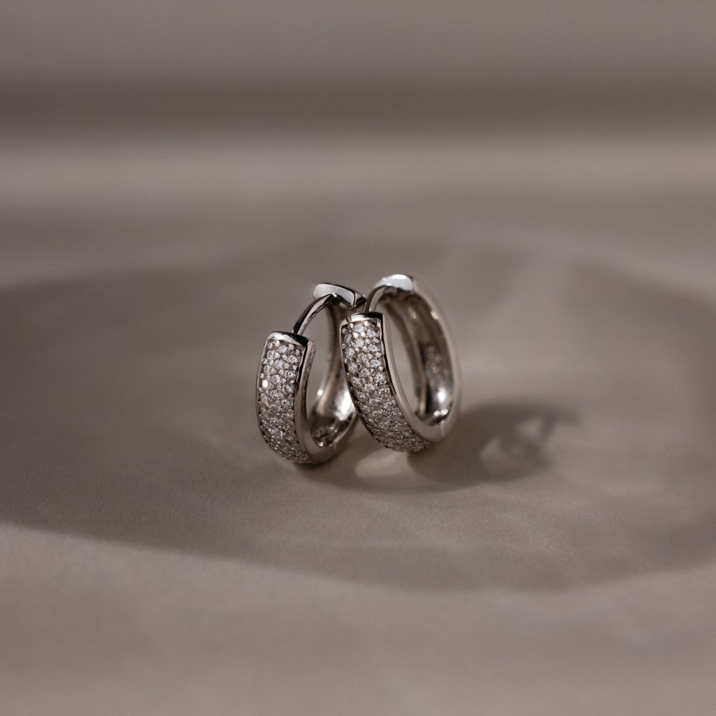 Pair of silver hoop earrings on a beige background