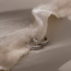 Pair of silver pave hoop earrings on beige fabric