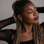 Woman with braided hair wearing various silver earrings against a neutral background