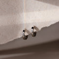 Silver hoop earrings on a textured beige surface