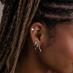 Close-up of a model with various silver hoop earrings and braided hair.