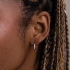 Close-up of an ear with a twisted hoop earring, focusing on the jewelry.