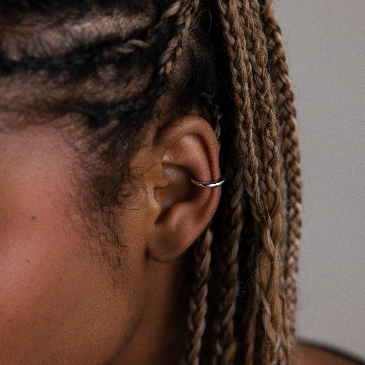 Close-up of a model with a silver cuff earring and braided hair.