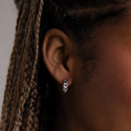 Close-up of a woman wearing a silver chain hoop earring with braided hair.