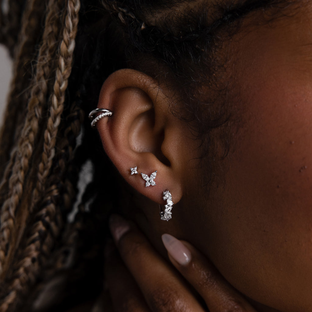 Close-up of an ear with multiple silver diamond earrings against a blurred background