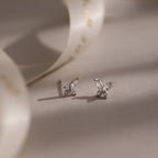 Pair of diamond silver butterfly earrings on a soft beige background