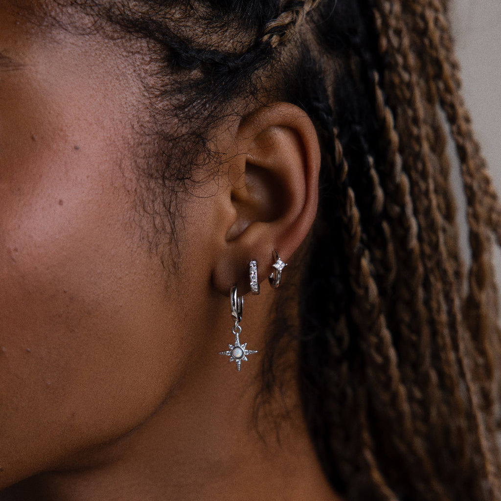 Close-up of an ear with silver hoop earrings and a star-shaped earring.