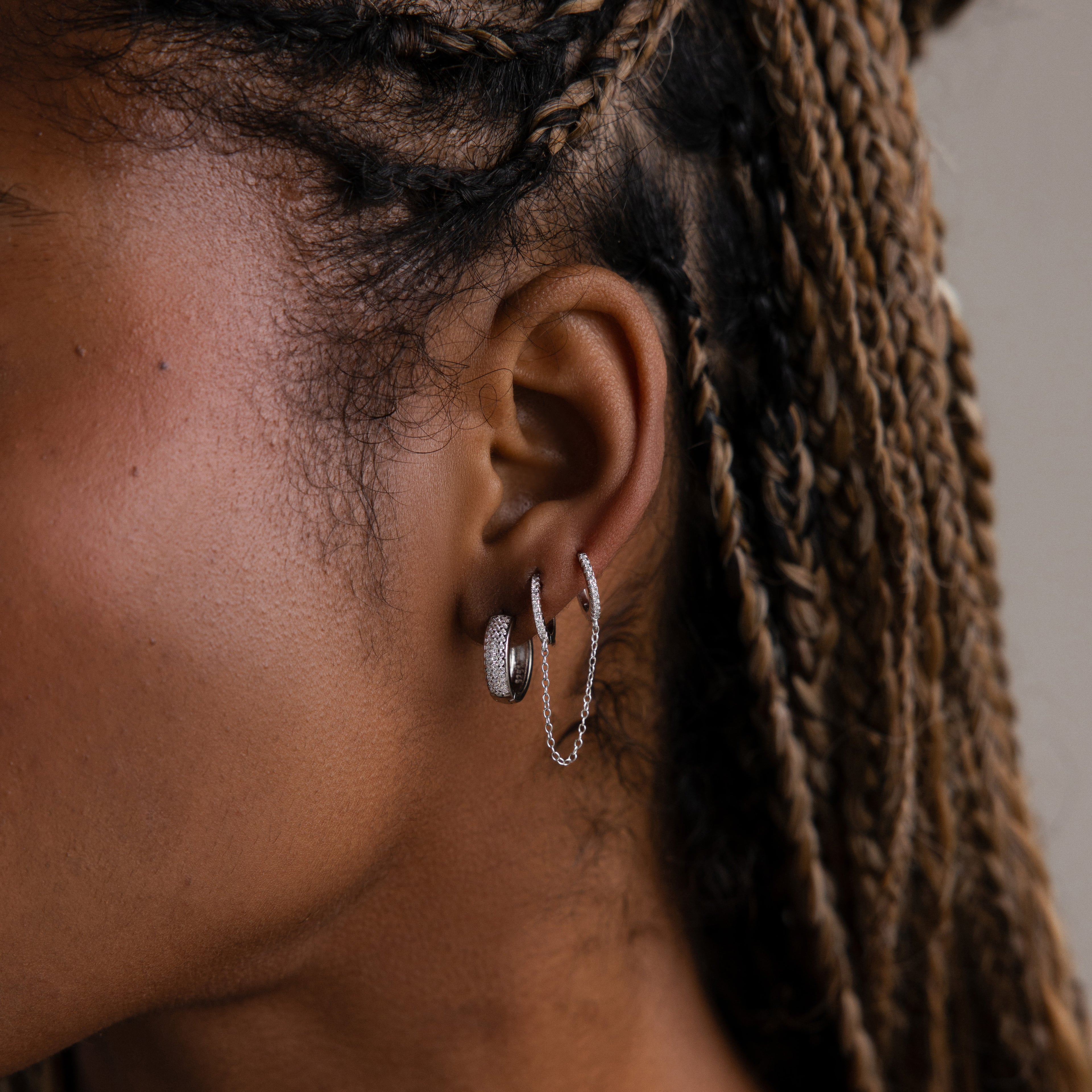 Close-up of a model with silver diamond hoop earrings and braided hair.