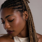 Woman with braided hair wearing a silver duo hoop earring against a neutral background