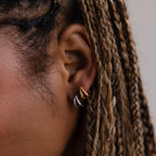 Close-up of a model with braided hair wearing silver and gold hoop earrings.