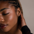 Close up side view of a model wearing tiny lightning bolt stud earrings, highlighting a delicate and modern earring look.