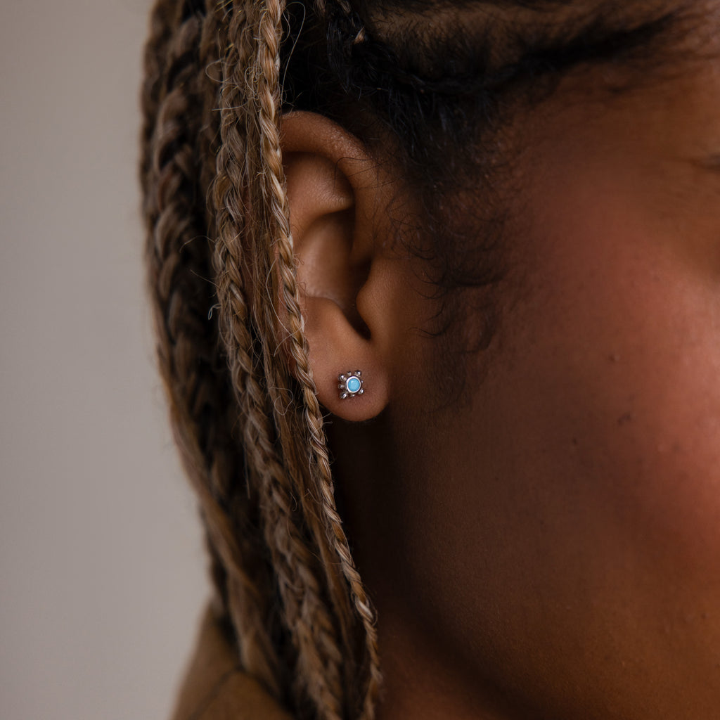 Close-up of a model with a silver turquoise stud earring and braided hair