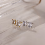 Two pairs of gold and silver stud earrings on a light background
