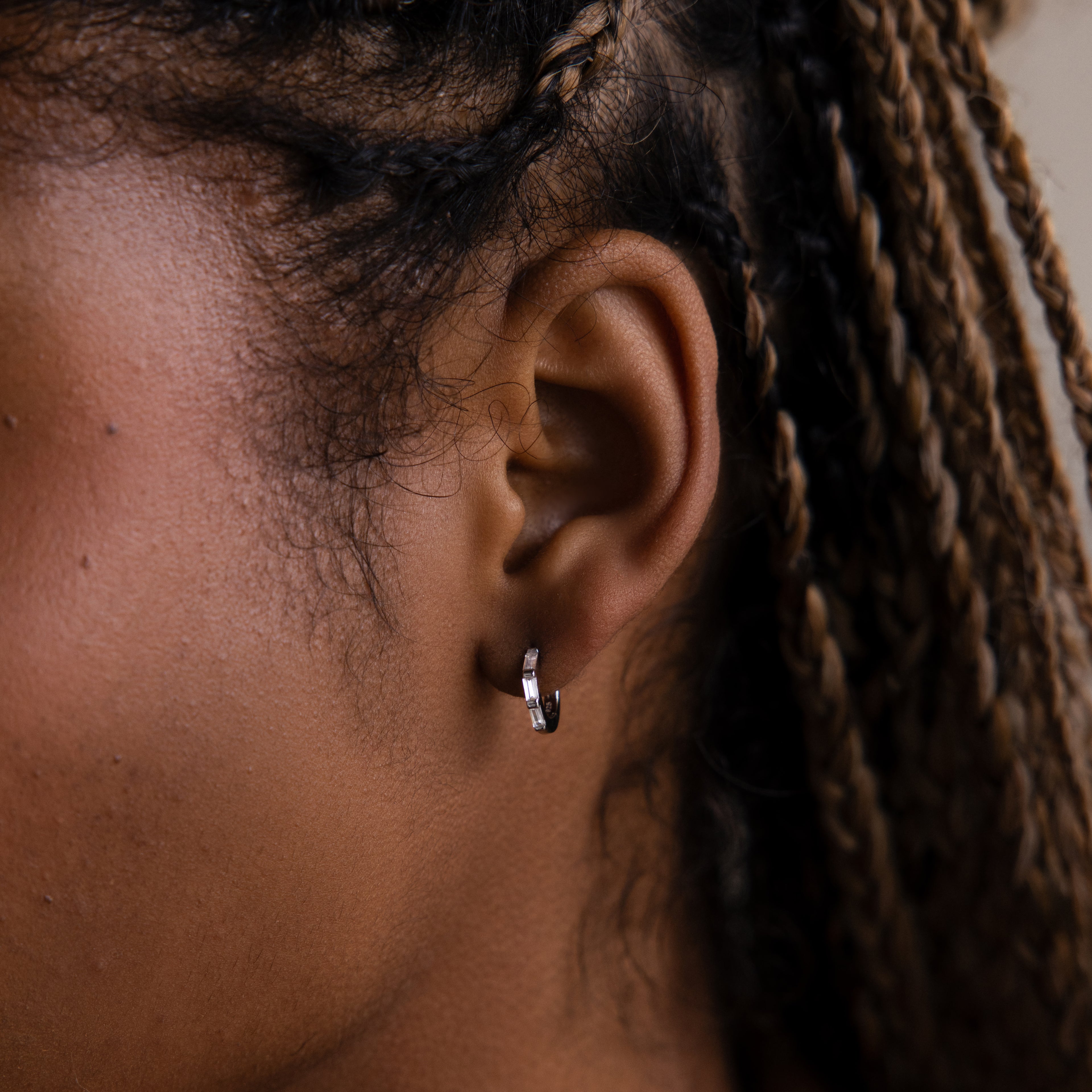 Close-up of a model with a silver hoop earring and braided hair.