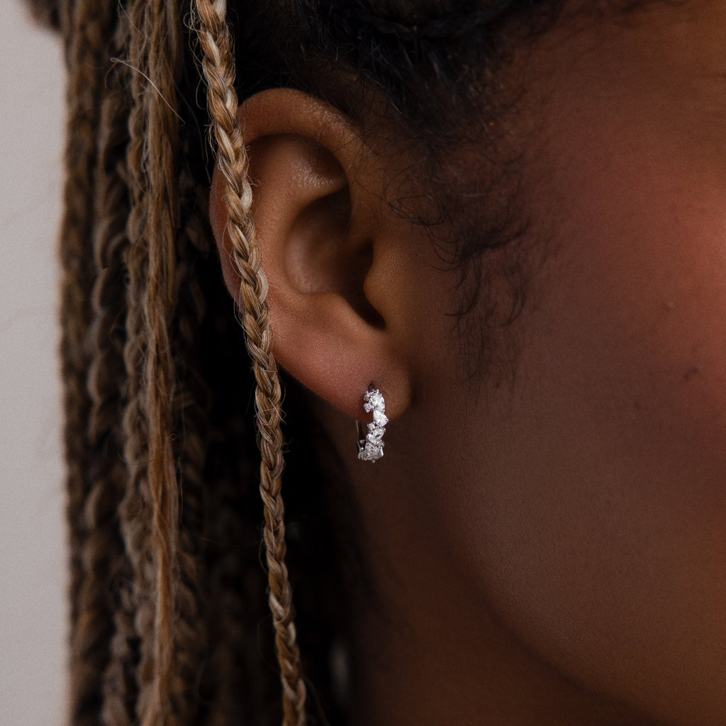 Close-up of a model wearing a silver diamond hoop earring with braided hair.