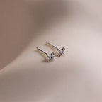 Pair of silver stud earrings with star-shaped diamond elements on a beige background