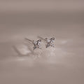 Pair of silver stud earrings with small diamonds on a reflective surface.