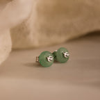 Close-up of silver Jade Bird Studs with dainty silver dove birds on round green jade discs.