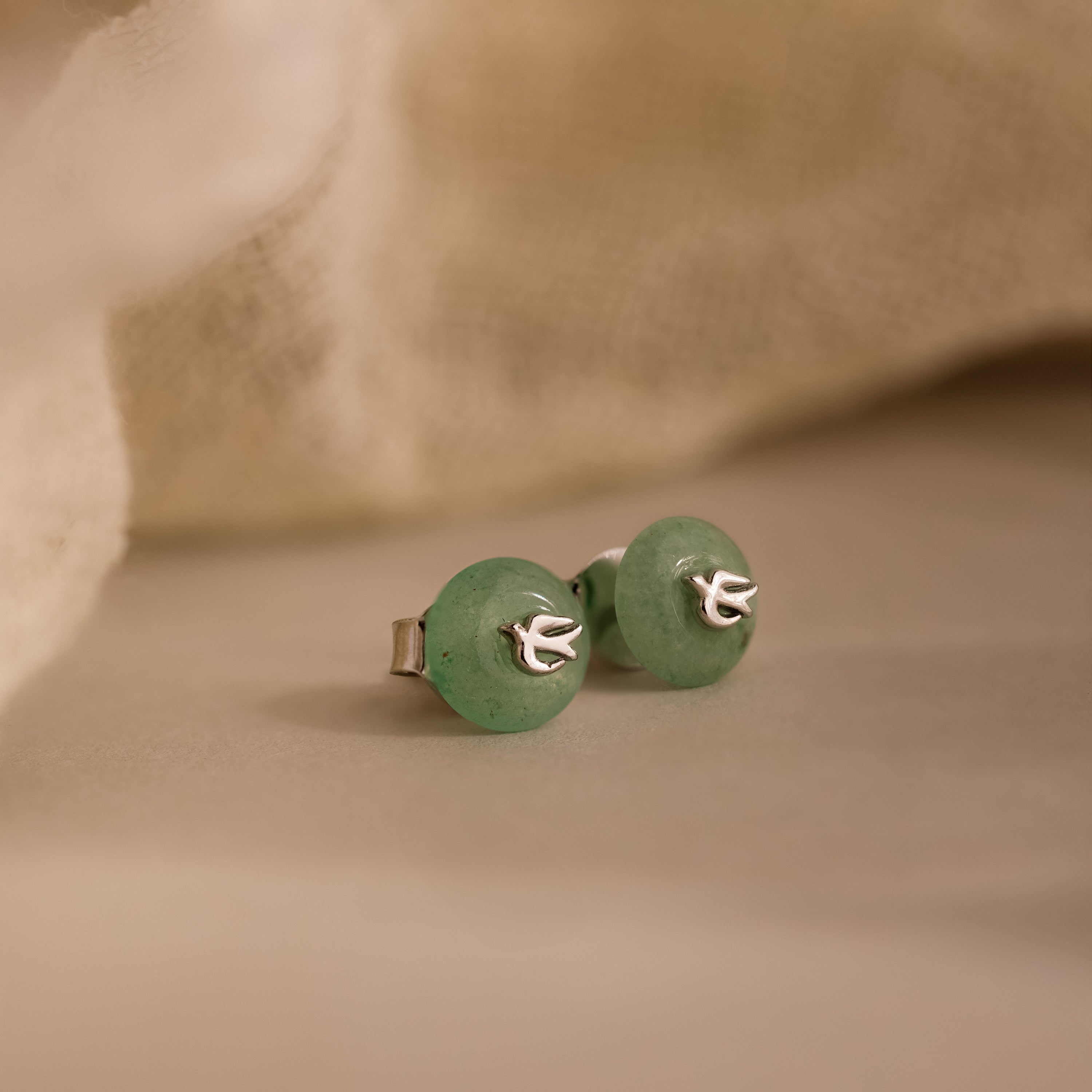 Close-up of silver Jade Bird Studs with dainty silver dove birds on round green jade discs.