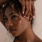 Close-up of a model's ear wearing a twisted silver hoop earring with a green jade teardrop pendant.
