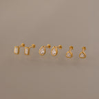 The Diamond Bezel Flatback Studs Set features three pairs of classic stud earrings—rectangular, teardrop, and round clear gemstones—shown on a neutral background.