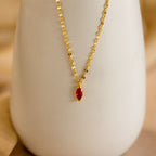 Custom Marquise Birthstone Necklace with a red marquise-cut pendant, showcased on a sleek white cylinder.