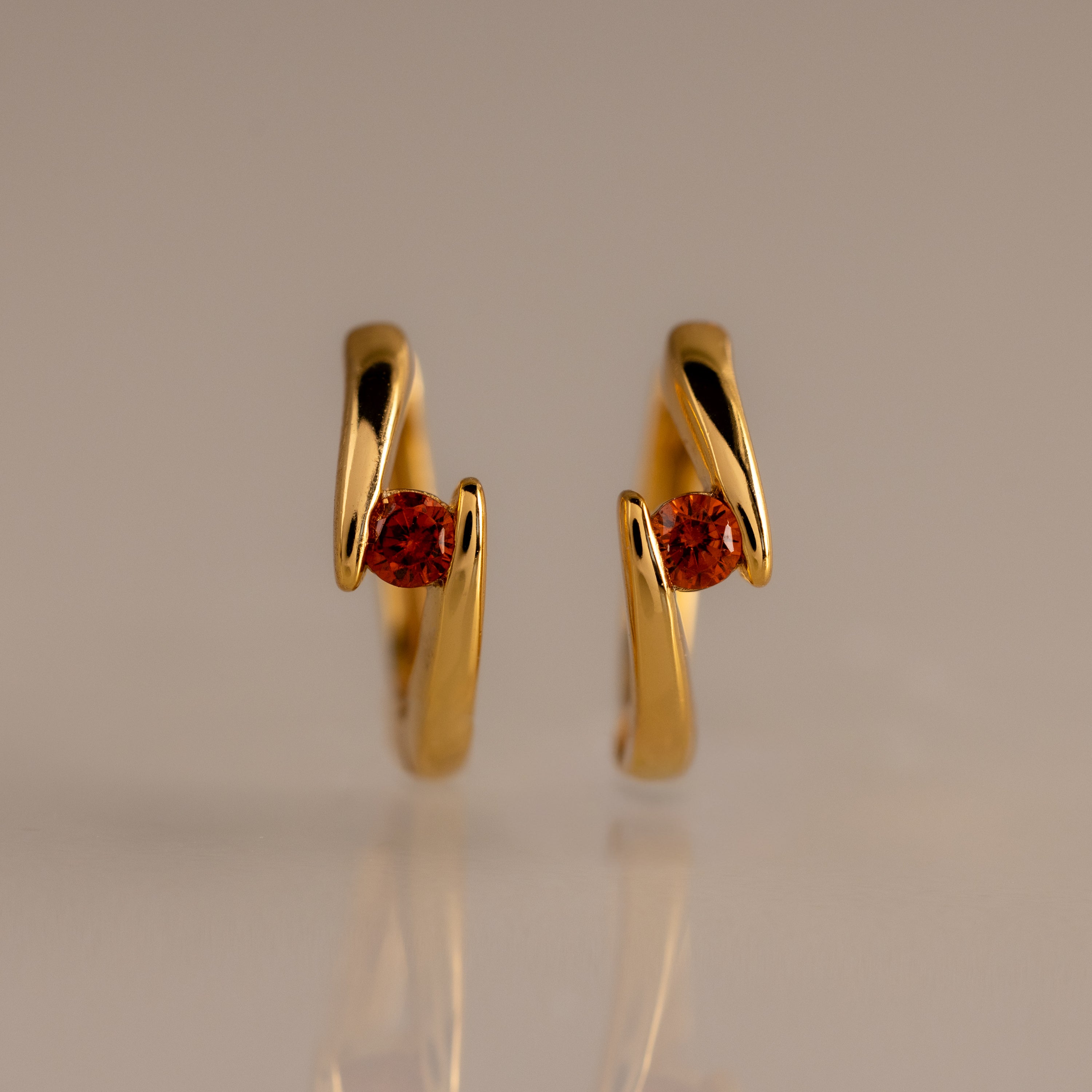 Floating Garnet Huggies: Twisted gold hoop earrings with a wavy design, each featuring a round garnet center—perfect personalized jewelry for birthstone lovers.