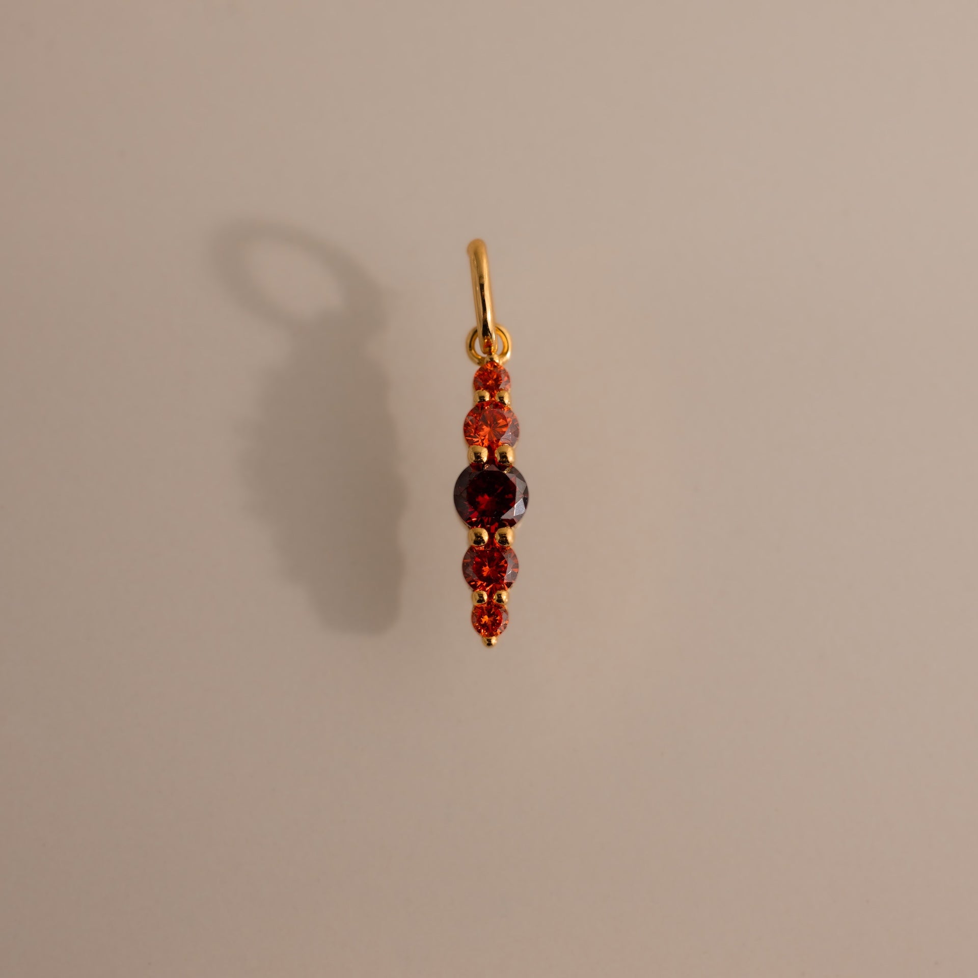 The Ombre Lace Garnet Charm is a gold pendant with red and purple gemstones set vertically—an elegant, personalized charm and perfect gift for a birth month.