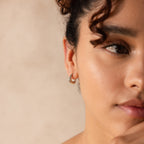 Close-up of model wearing a silver geometric chunky hoop earring.