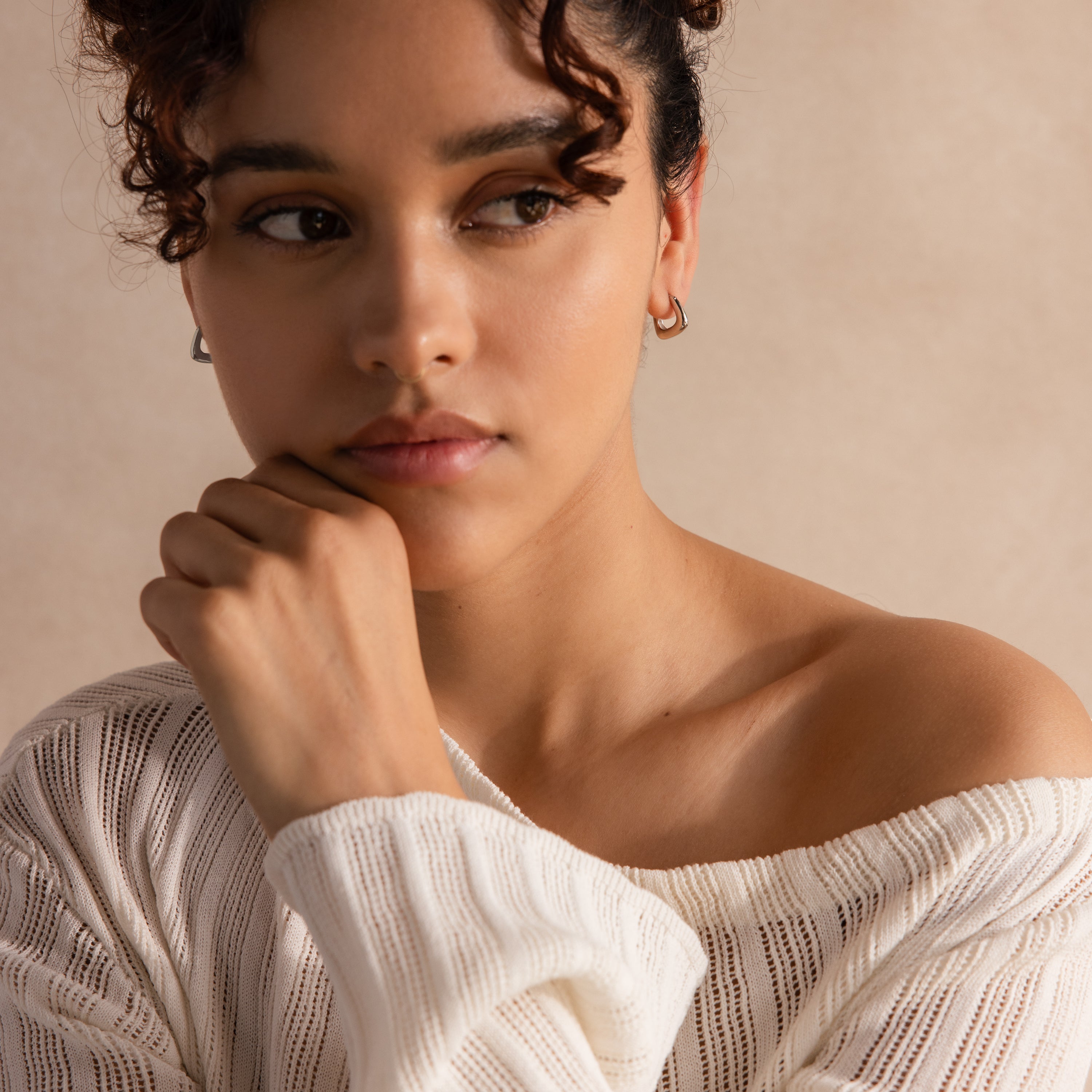 Model wearing silver geometric square hoop earrings, styled with a knit top.