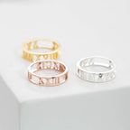 The Roman Numerals Ring in Rose Gold, featuring cut-out numerals, is perfect for celebrating a meaningful date or milestone.