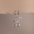 Dangling Silver earrings shaped like roses on a beige background